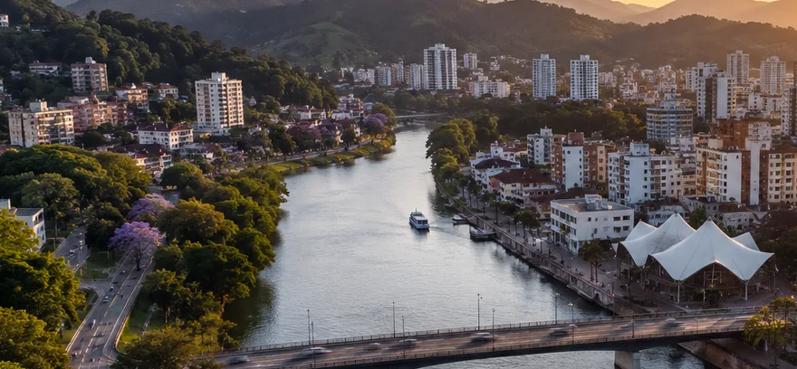 Vista aérea de Blumenau ao entardecer, com o rio Itajaí-Açu cortando a cidade