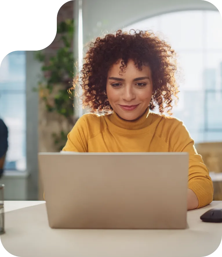 Maria de Souza sorrindo enquanto usa o notebook