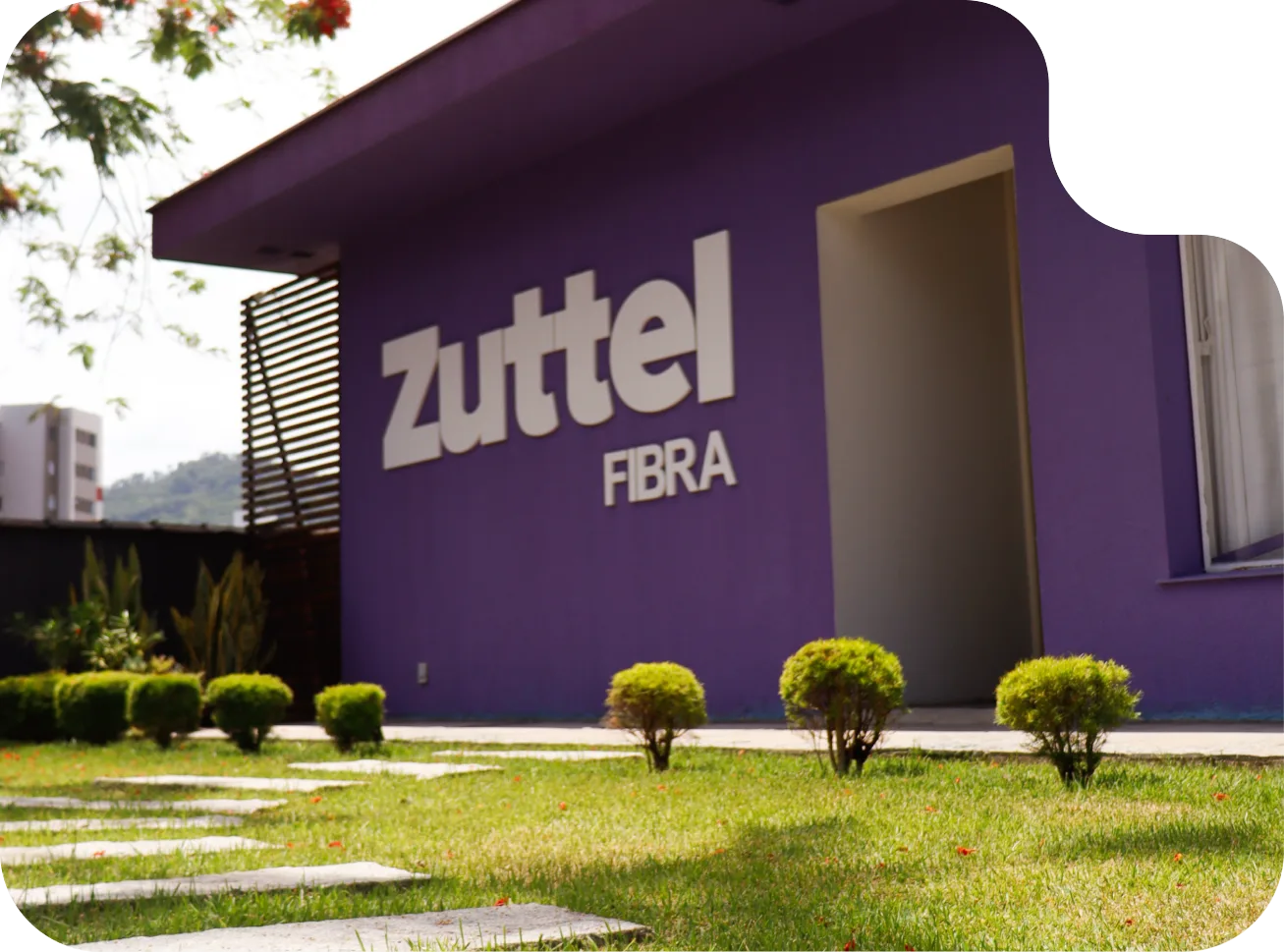 Fachada roxa da sede da Zuttel Fibra, com jardim na frente