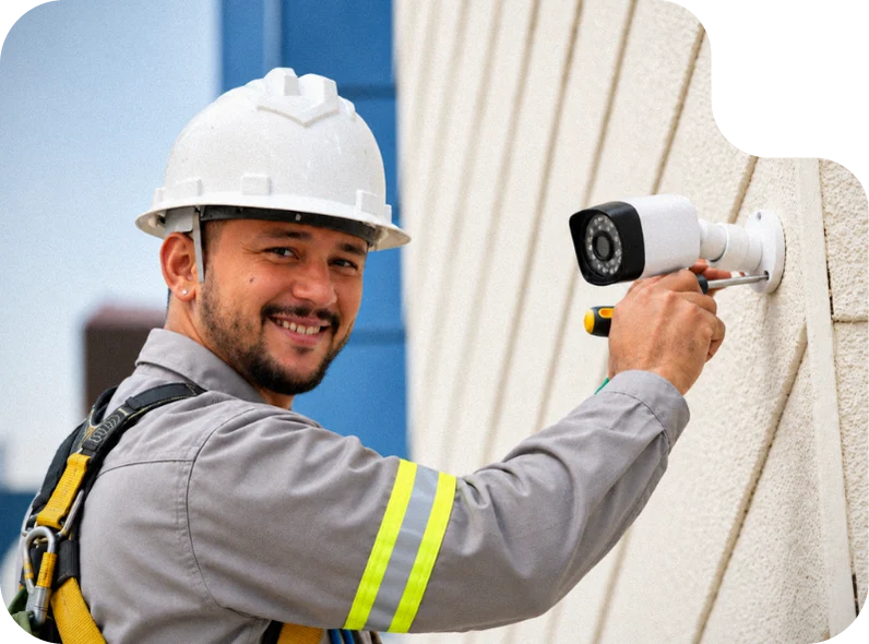 Técnico instalando uma câmera de segurança na fachada de um prédio